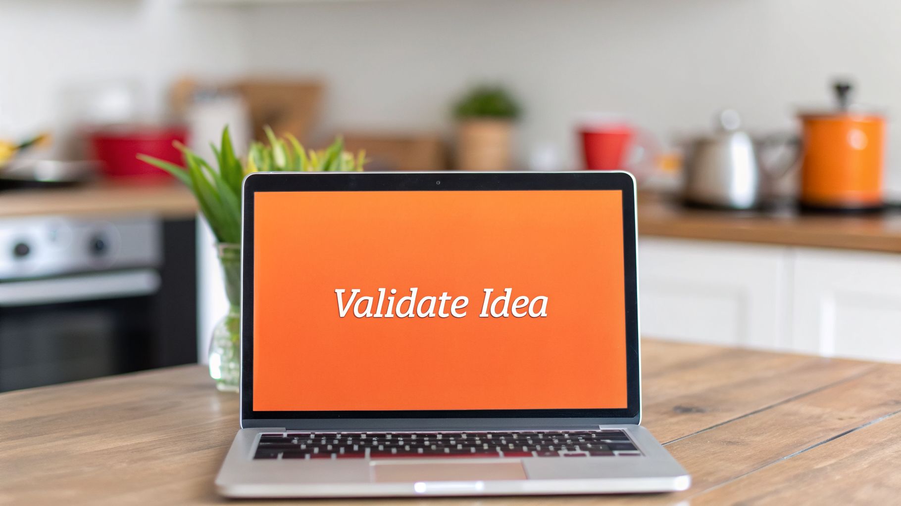 A laptop displaying "Validate Idea" on its orange screen, placed on a wooden table in a kitchen.
