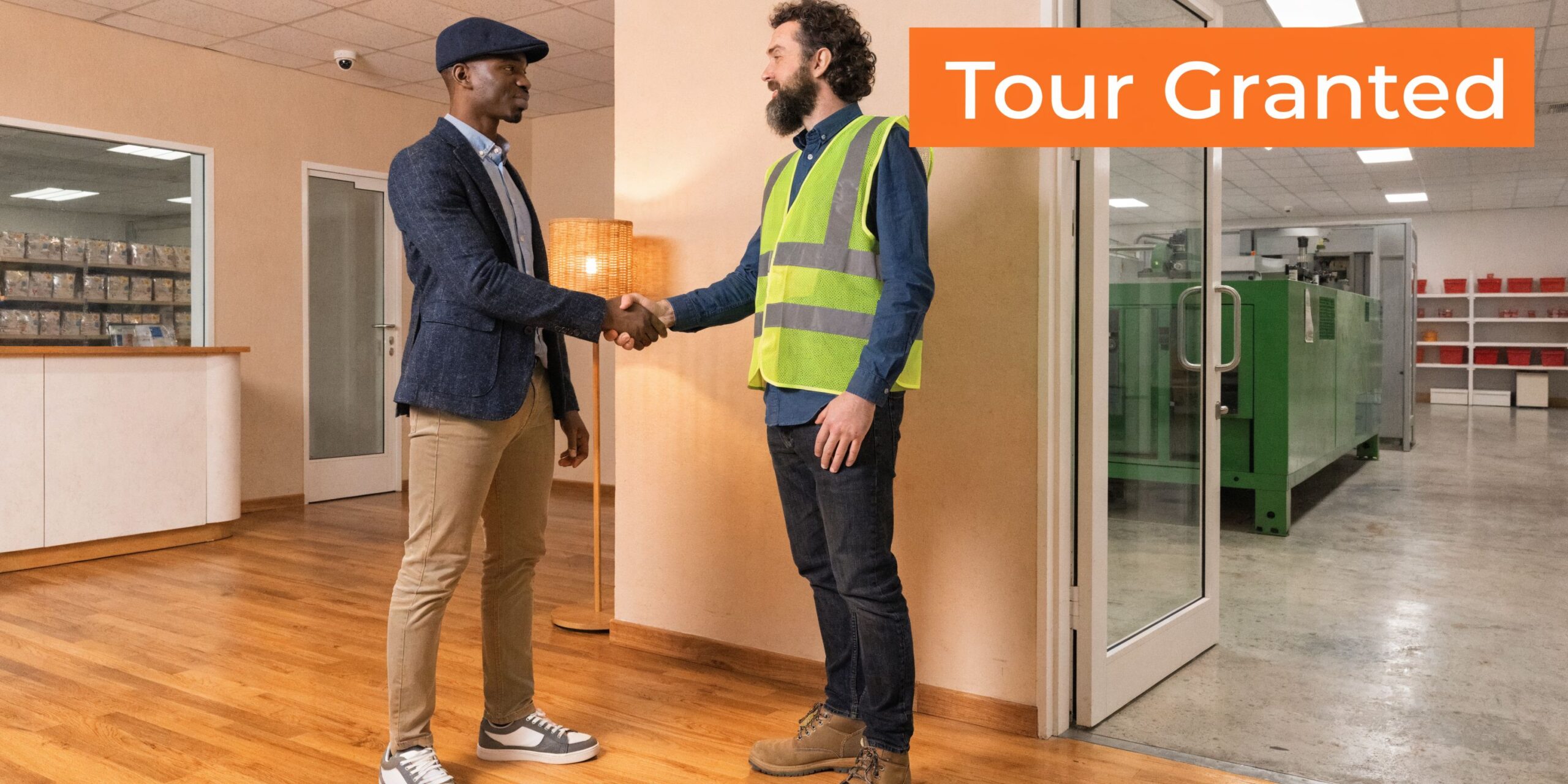 A professional in business attire shaking hands with a factory worker wearing a high-visibility safety vest.