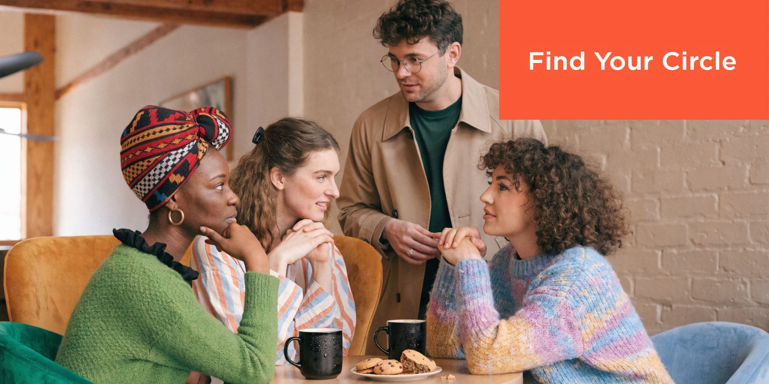 A diverse group of four friends chatting and having coffee together in a bright, cozy cafe.