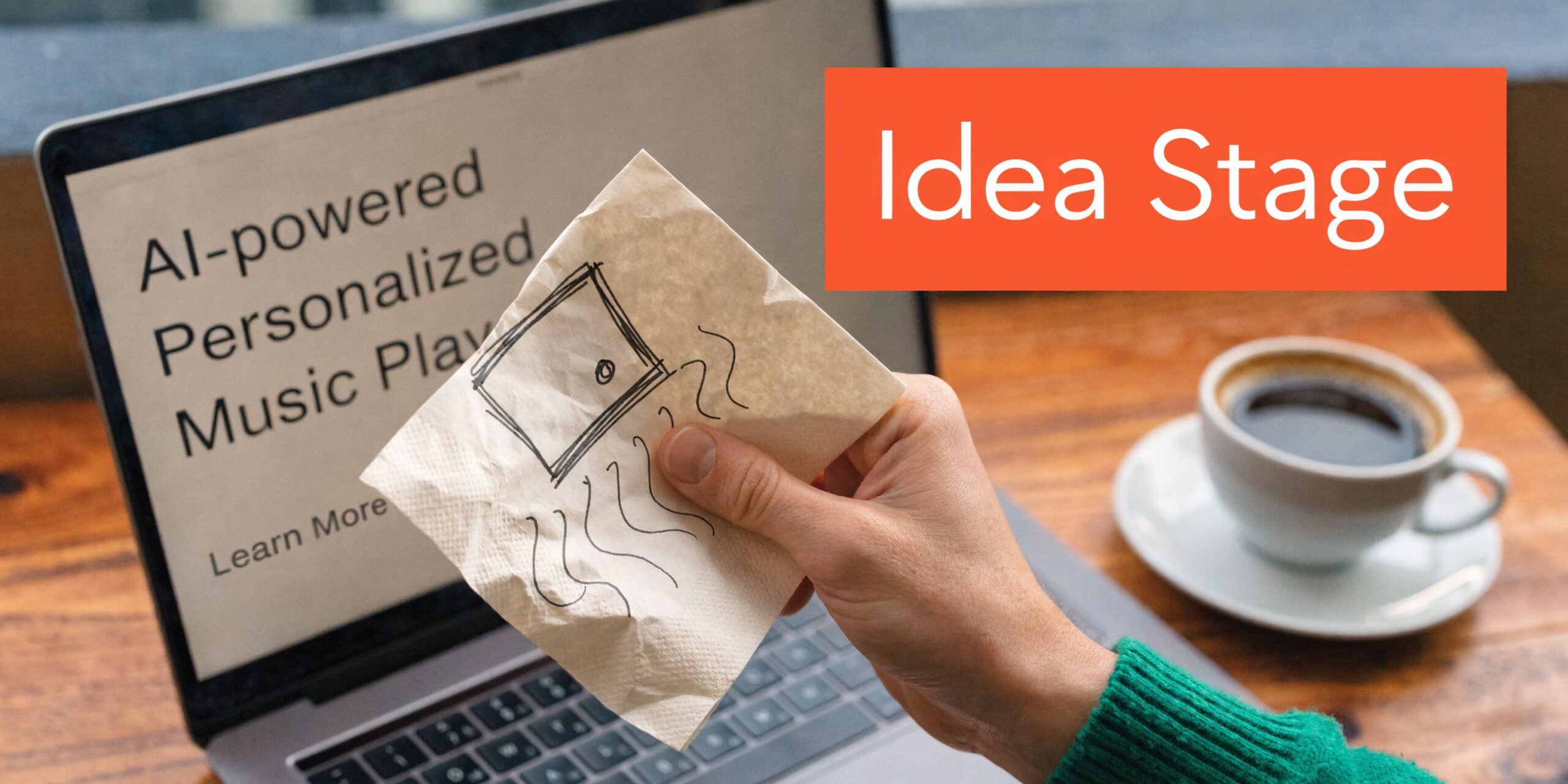 A hand holds a napkin with a rough sketch over a laptop displaying a business concept idea.