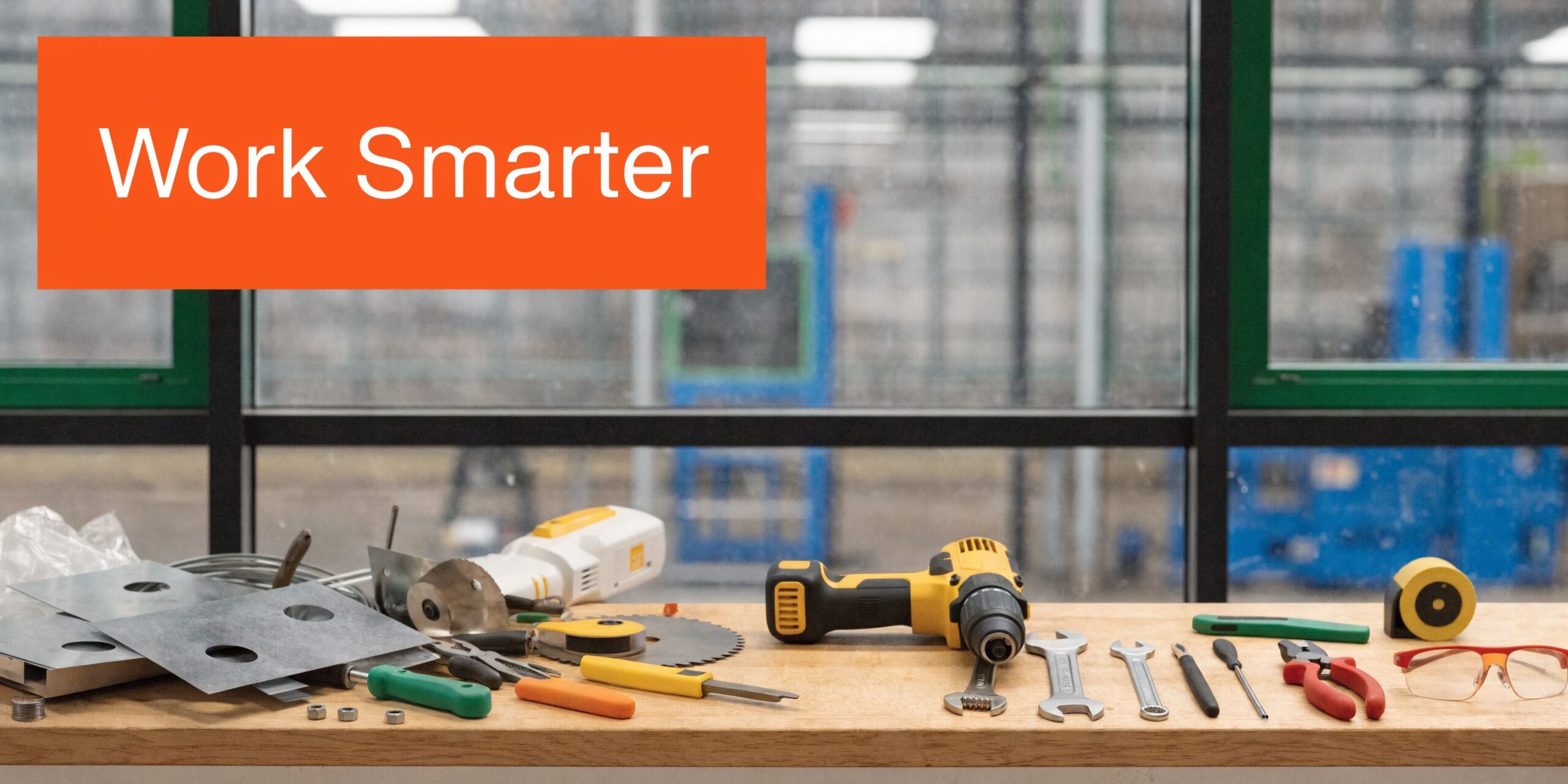 Various construction tools and metal plates arranged on a wooden workbench in a professional industrial workshop setting.