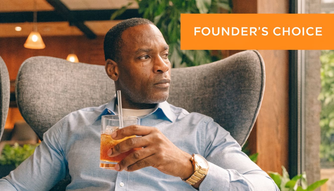 A middle-aged man in a blue shirt sits in a chair holding a glass of iced tea.