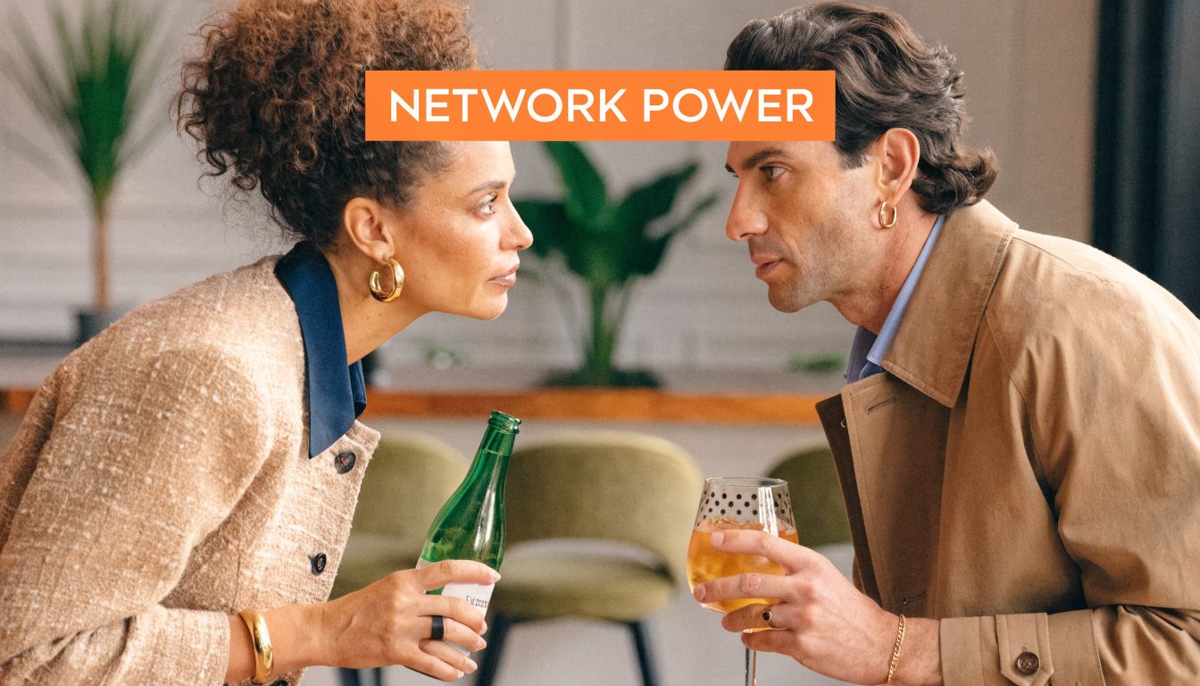 A sophisticated woman and man in stylish attire having a conversation while holding drinks indoors.
