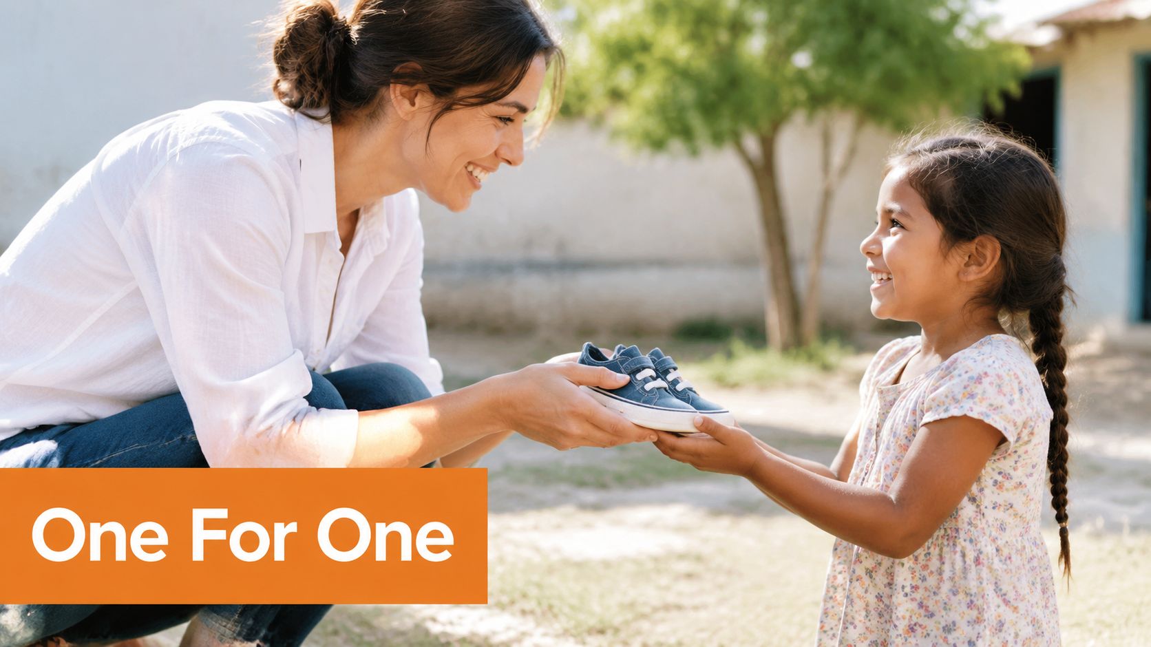 A smiling woman hands a pair of blue shoes to a young girl in an outdoor setting.