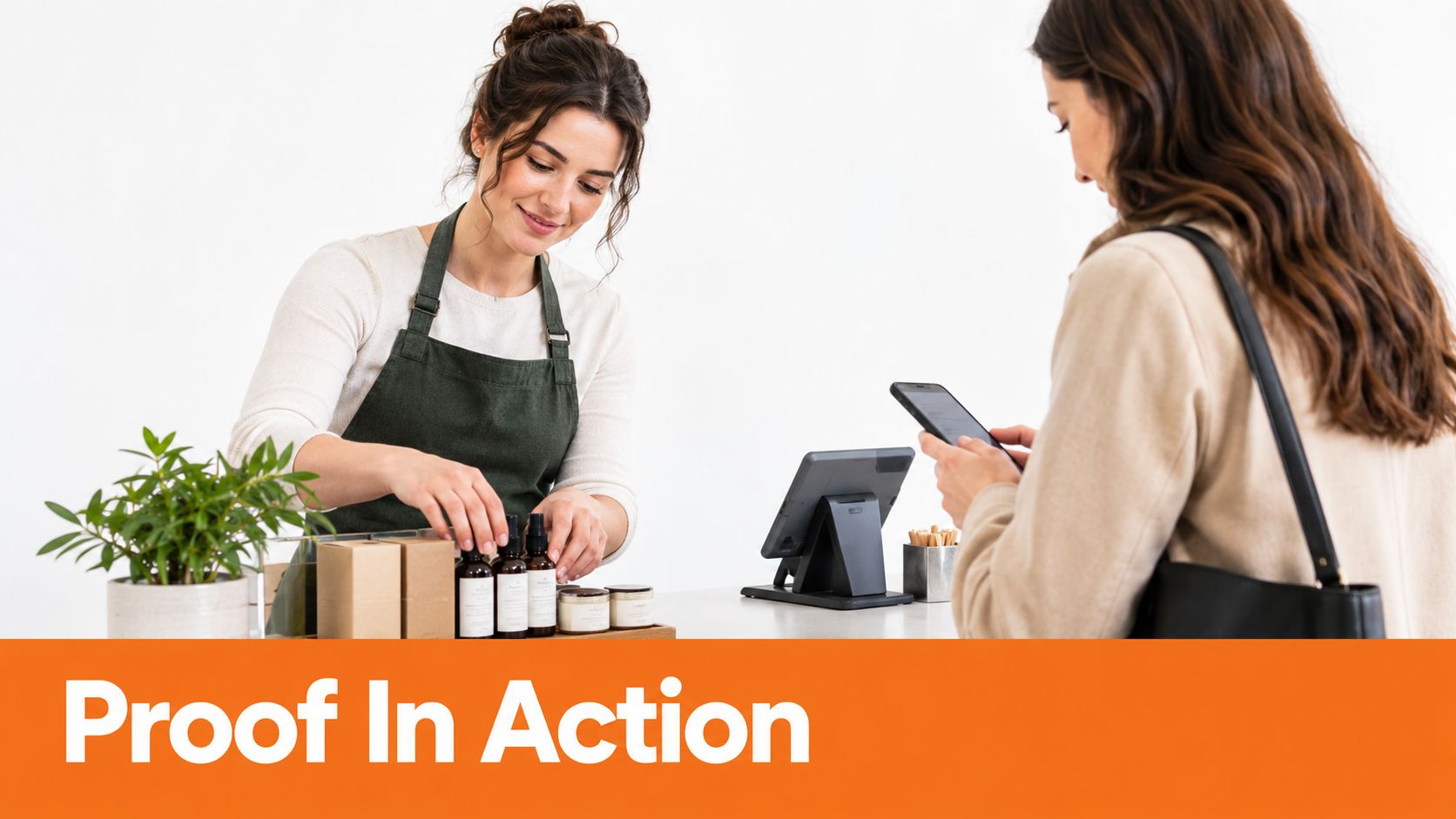 A friendly shop assistant helping a customer at a store counter while the customer uses their phone.